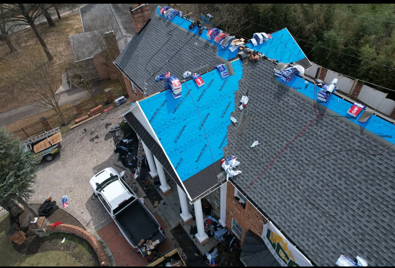 Drone view of an LCR roof replacement on a brick Northern Virginia colonial, underlayment down and crew truck below