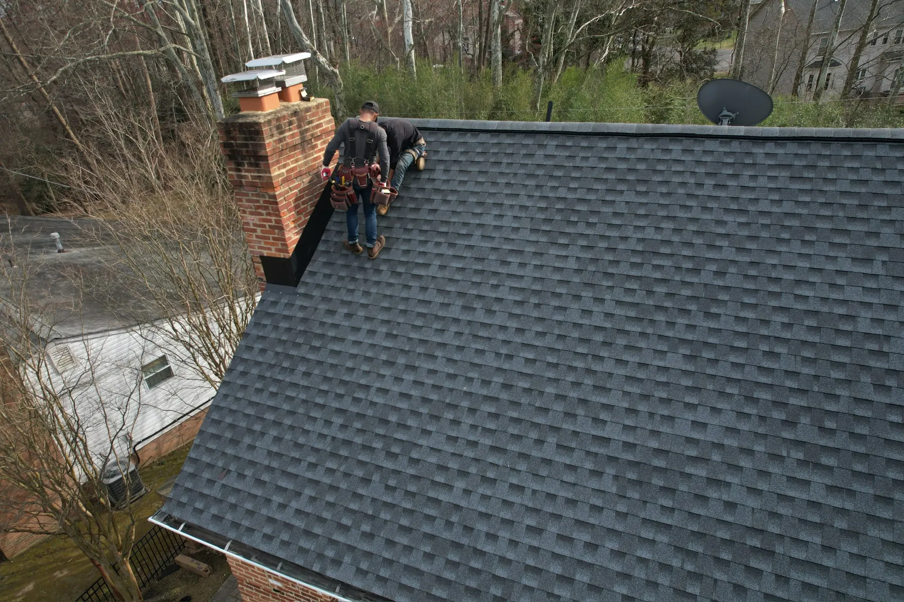 LCR roofer working at the chimney of a newly installed architectural shingle roof