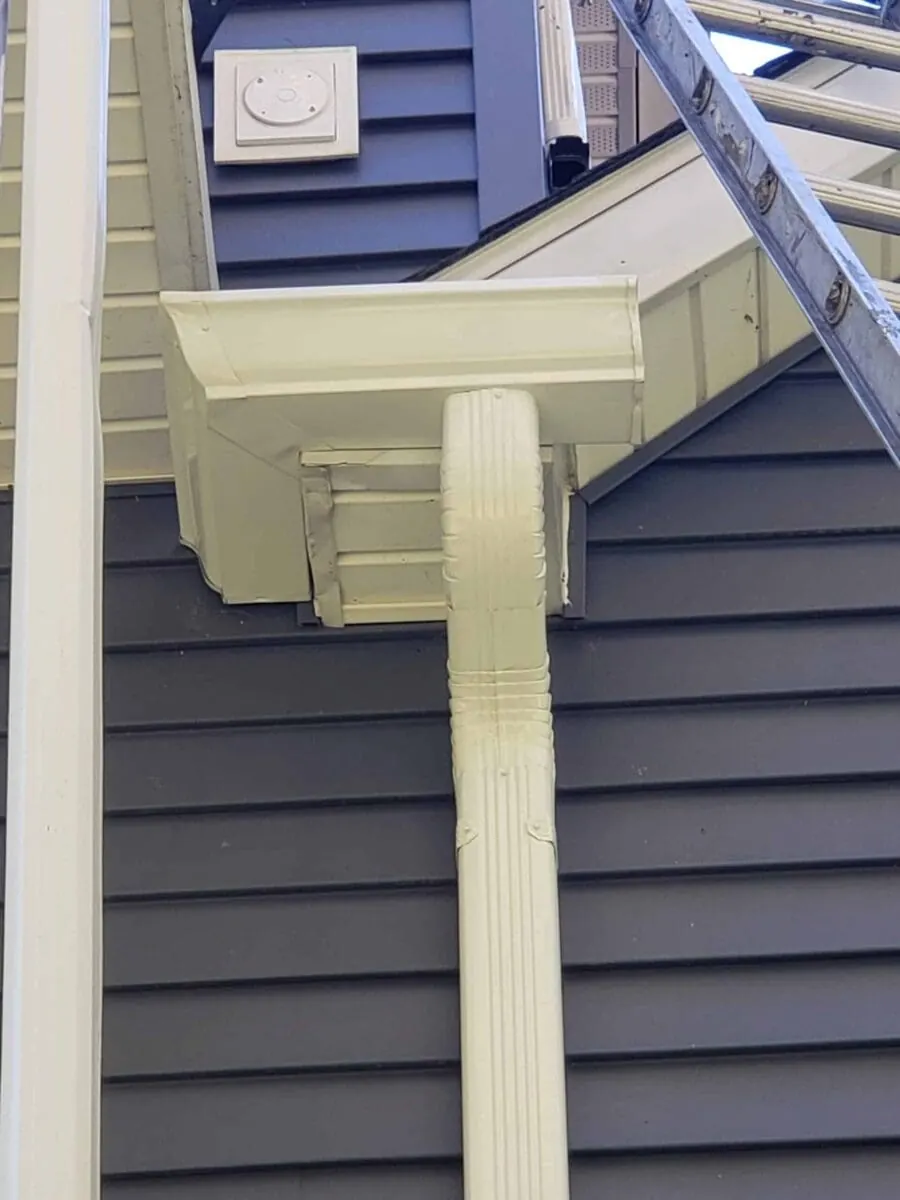 New seamless aluminum gutter and downspout corner installed on dark siding