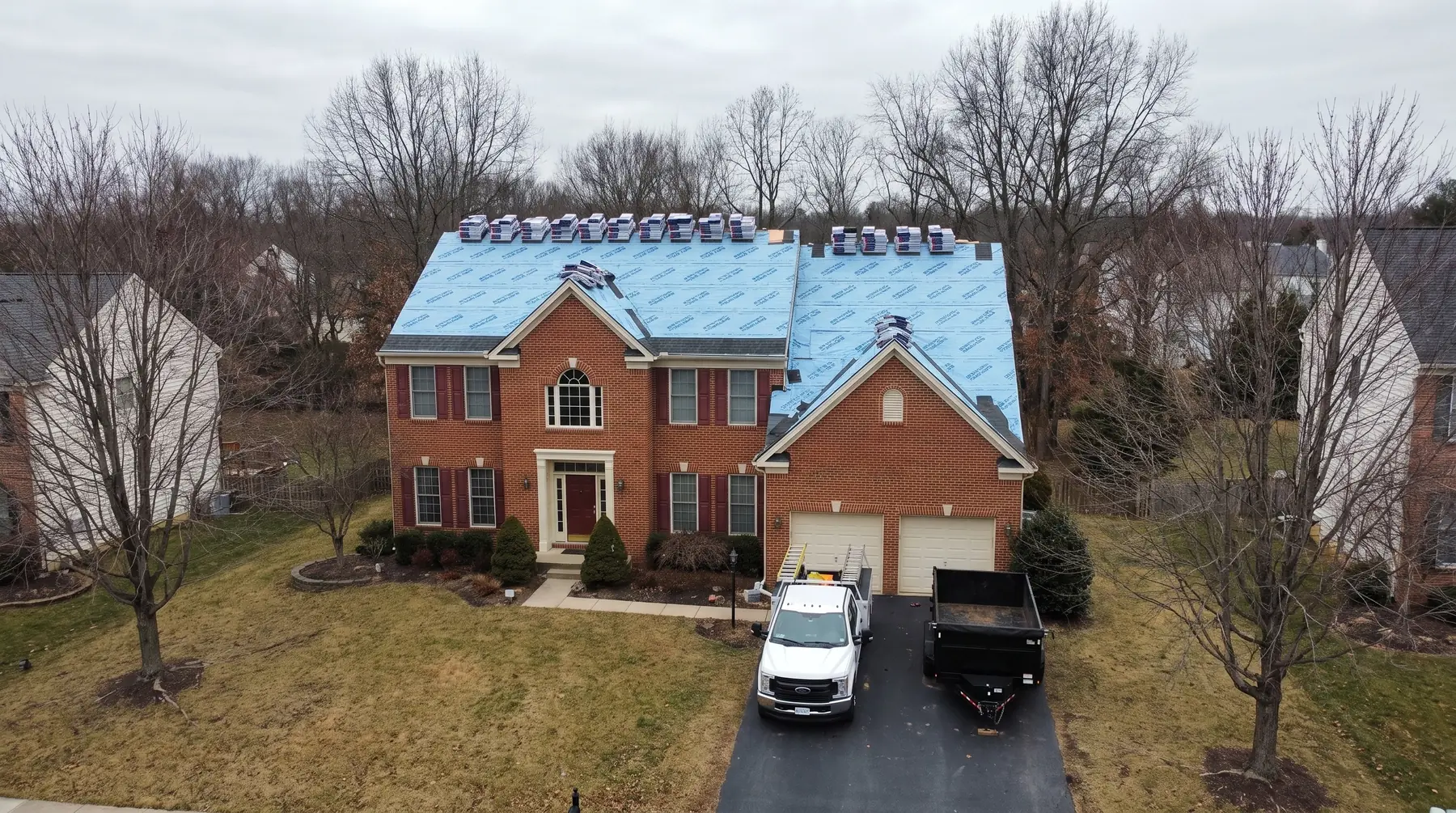 Drone aerial of a Northern Virginia home mid-roof replacement, overcast sky, completed LCR install