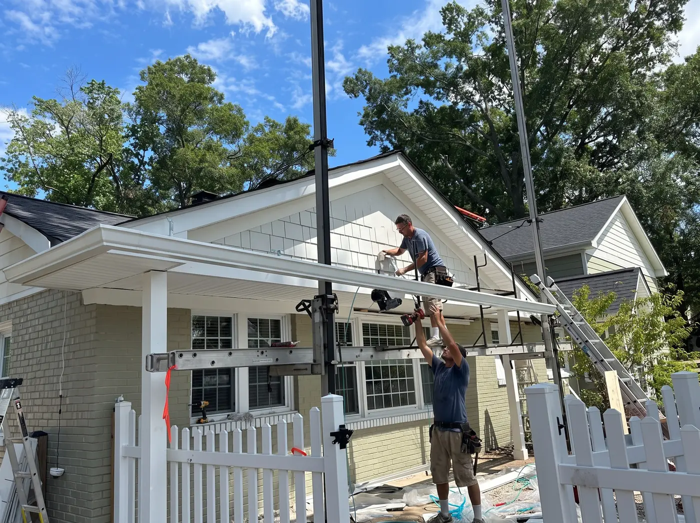 LCR worker on an extension ladder installing seamless aluminum gutter on a Northern Virginia home, candid on-site documentation